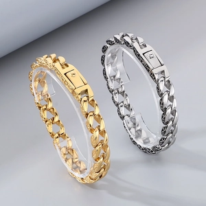 Close-up of gold and silver Cuban chain bracelets with intricate engraved pattern detailing