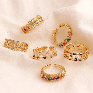 Collection of gold-plated geometric open rings with colorful cubic zirconia on linen