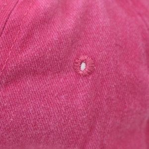 Detail of pink washed cotton baseball cap showing high-quality embroidered eyelets