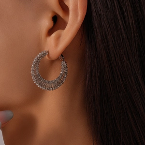Close-up of model wearing wide silver hoop earrings with multi-row pavé crystals
