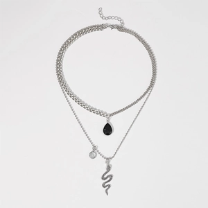 Detail view of double-layer necklace with curb chain, snake pendant, and black gemstone