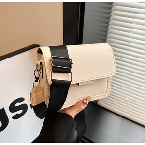 Detail of off-white rectangle crossbody bag featuring a wide black nylon shoulder strap