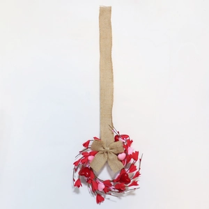 Détail d'une couronne en forme de cœur avec des baies rouges et un nœud en toile de jute