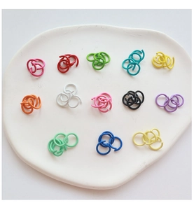 Colorful metal jump rings in various vibrant colors on a white ceramic tray for DIY jewelry