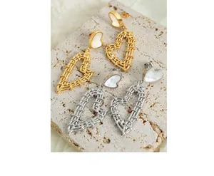 Detailed view of gold and silver heart-shaped woven earrings on textured stone