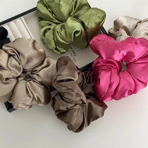 Close-up of assorted silk satin scrunchies in vibrant colors like green and magenta