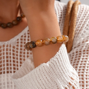 Close-up of amber acrylic beaded necklace worn with a white mesh knit sweater