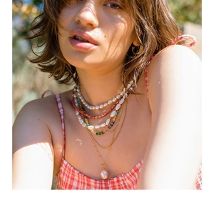 Close-up of layered necklaces with colorful beads and baroque pearl pendant on model