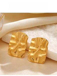 Detail of 18K gold plated earrings with irregular wrinkled texture on a stone surface
