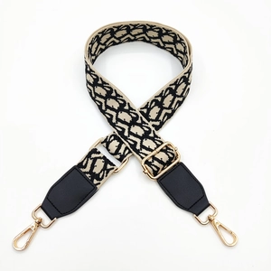Detail of adjustable woven jacquard bag strap with leather ends and golden metal hooks