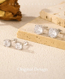 Detailed macro of rose-cut silver stud earrings on a textured stone with dry leaves