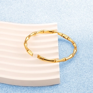 Elegant gold bamboo joint bangle in polished stainless steel on a blue luxury background