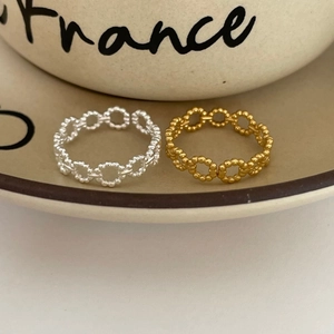 Macro detail of minimalist gold and silver beaded hollow chain rings on ceramic