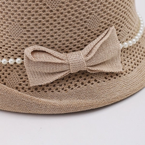 Détail d'un chapeau de soleil en tricot beige avec nœud délicat et rangée de perles