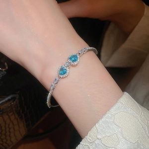 Detailed view of luxury heart water-drop zircon bangle with blue gemstones on wrist