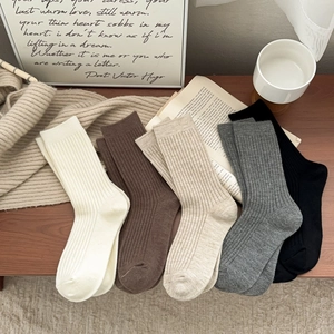Detailed view of five neutral-toned knitted crew socks with classic vertical rib textures