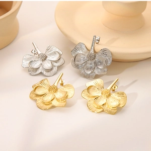 Macro detail of multi-layered flower stud earrings in polished gold and silver finishes