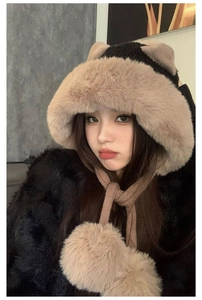 Dettaglio di un cappello invernale in peluche con orecchie e lacci con pompon sul modello