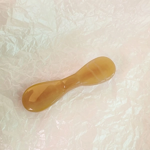 Vue détaillée d'un bâton de massage facial ambré sur fond de papier rose
