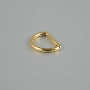 Detailed view of the polished gold D-ring titanium piercing jewelry with zircon inlay