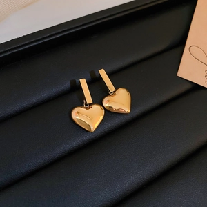 Detail view of gold heart drop earrings with high polish finish on black leather tray