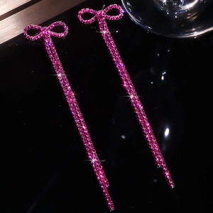 Detailed macro view of hot pink rhinestone bow earrings with long sparkling tassels