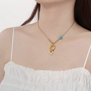 Detail of 18K gold plated heart necklace with turquoise beads and pearl drop on model