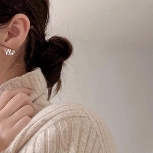 Close-up of minimalist textured silver hoop earrings worn with a cozy knit sweater