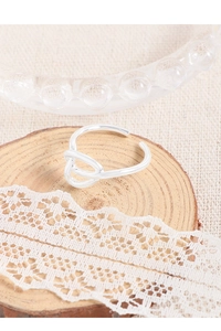 Detailed view of silver knotted open ring on a wooden slice with lace decor