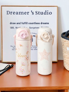 Cute stainless steel thermos bottles with bloom and star patterns on wooden surface