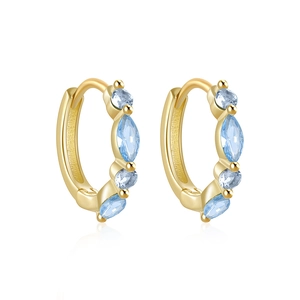 Macro detail of gold hoop earrings with marquise and round light blue zircon stones