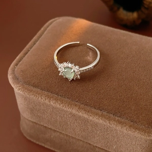 Macro shot of silver vintage adjustable sunflower ring with green gemstone on velvet box