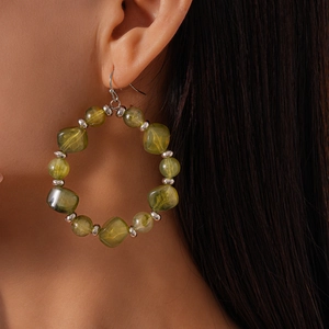 Close-up of green acrylic beaded hoop earrings with silver spacers on model