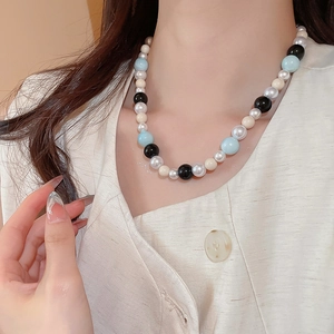 Detail of beaded necklace with blue and cream pearls worn on neck for a stylish look