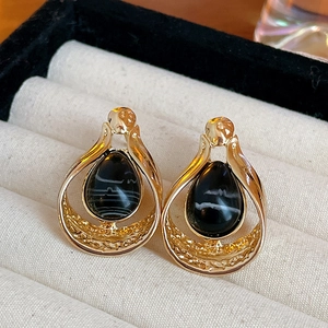 Detail of vintage teardrop earrings with gold hollow frame and black agate stones