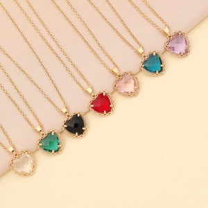 Detailed view of colorful heart-shaped zircon necklaces in gold settings on beige fabric