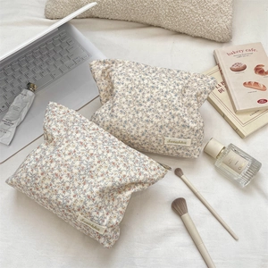 Close-up of corduroy floral makeup bags with brand label and metal zipper on white fabric