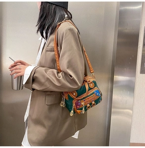 Detail of green and brown PU leather crossbody bag with colorful rivets and metal charms