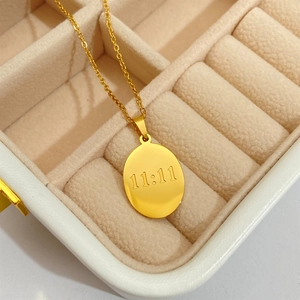 Detail of gold oval pendant necklace with 11:11 engraving in a cream jewelry box