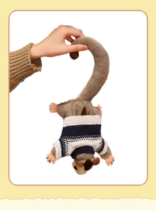 Close-up of sugar glider plush toy wearing a blue and white knitted sweater with long tail