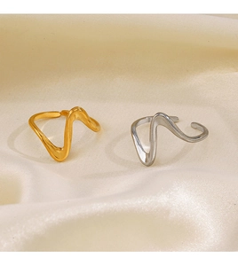 Detailed view of wave-shaped stainless steel rings in gold and silver on silk