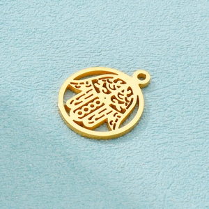 Macro shot of gold stainless steel Hamsa hand hollow pendant on blue background