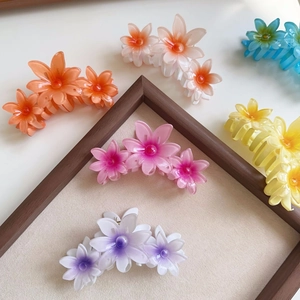 Detailed macro view of colorful flower claw clips in pink purple and blue on wooden frame