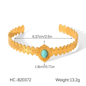 Detail view of gold leaf-textured bangle featuring an oval turquoise stone inlay