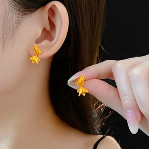 Boucles d'oreilles carpe koi dorées à texture brossée portées par un mannequin