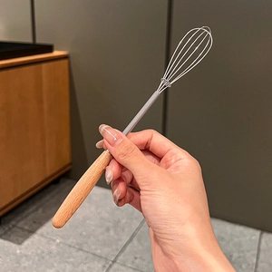 Detail of ergonomic wooden handle and stainless steel whisk for kitchen baking tasks