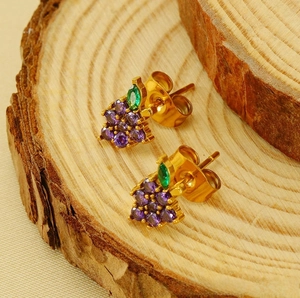 Close-up of 18K gold plated grape stud earrings with purple and green zircons on wood