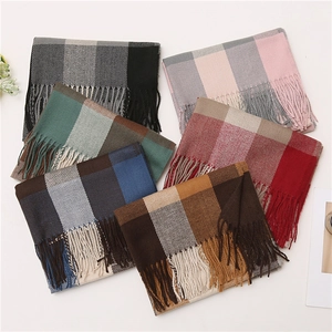 Flat lay detail showing six folded plaid scarves with tassels in various color combinations
