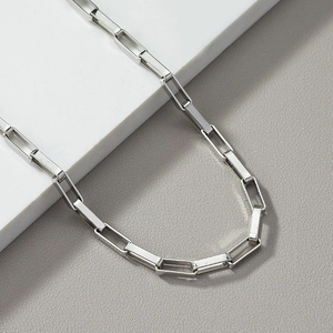Detail view of silver paperclip chain necklace with metallic luster on textured background