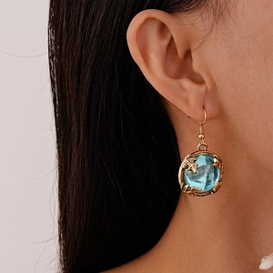Macro view of vintage gold leaf earrings with round blue gemstones on model